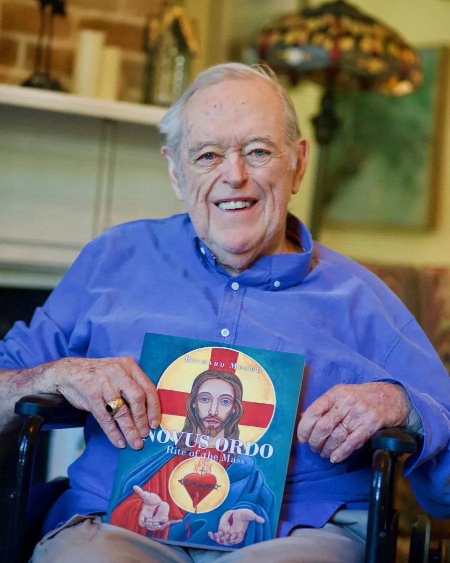 Richard Moore, smiling, holding his book Novus Ordo: Rite of the Mass.
